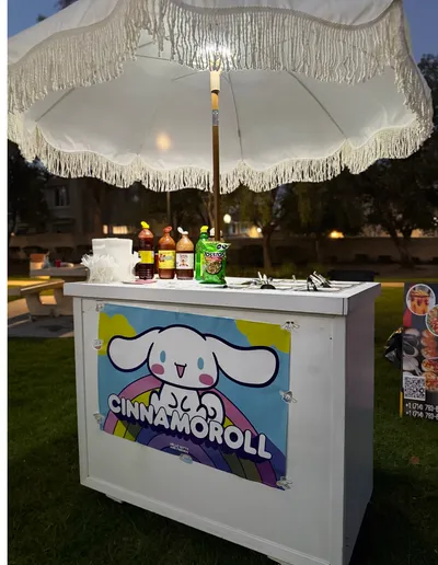 Snack cart decorated with a Cinnamoroll theme, set up outdoors at dusk