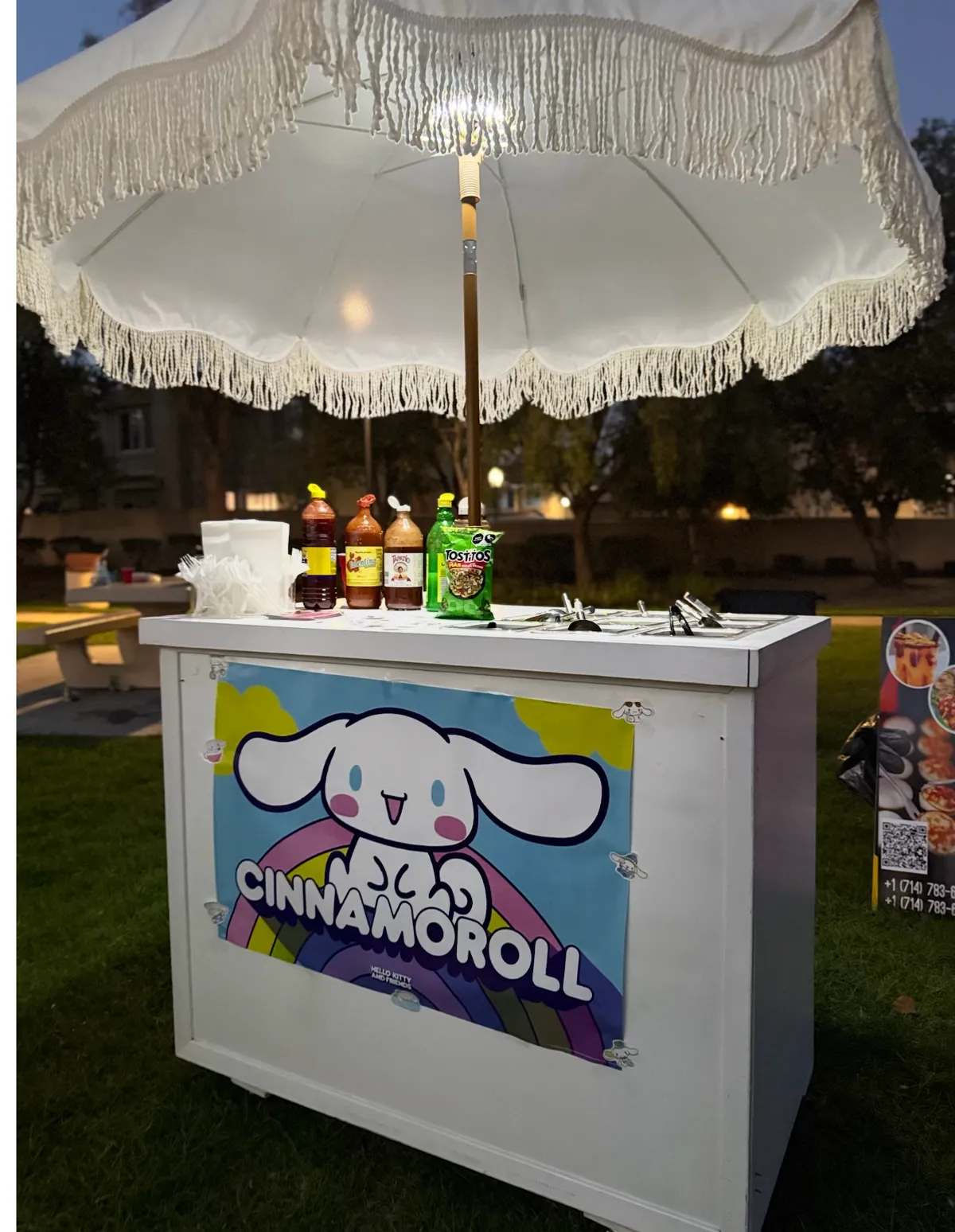 Snack cart decorated with a Cinnamoroll theme, set up outdoors at dusk